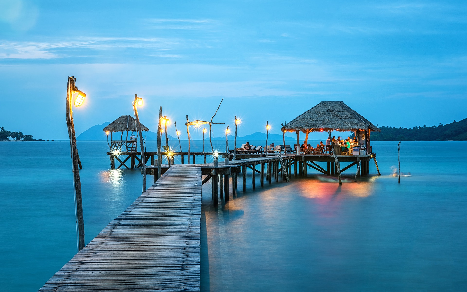 'Image taken on top of the ocean of a group of people dining at our island's hut'